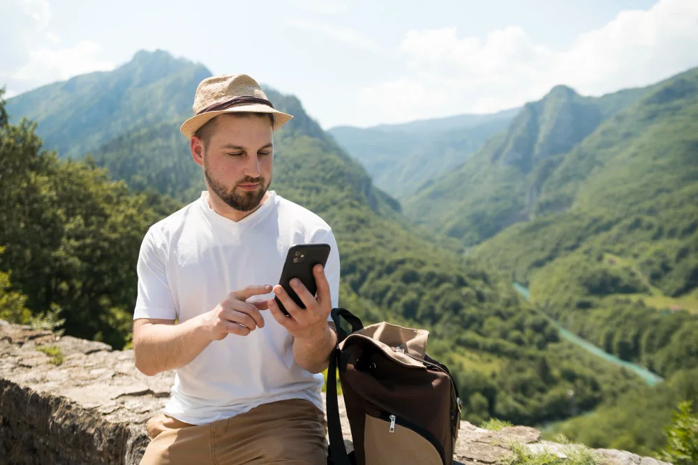 Alleinreisender Rucksacktourist in den Schweizer Alpen mit Handy – sicher und verbunden dank eSIM Schweiz