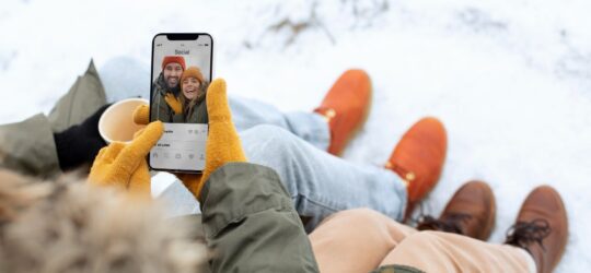 snow close up couple hands holding smartphone social media 540x250