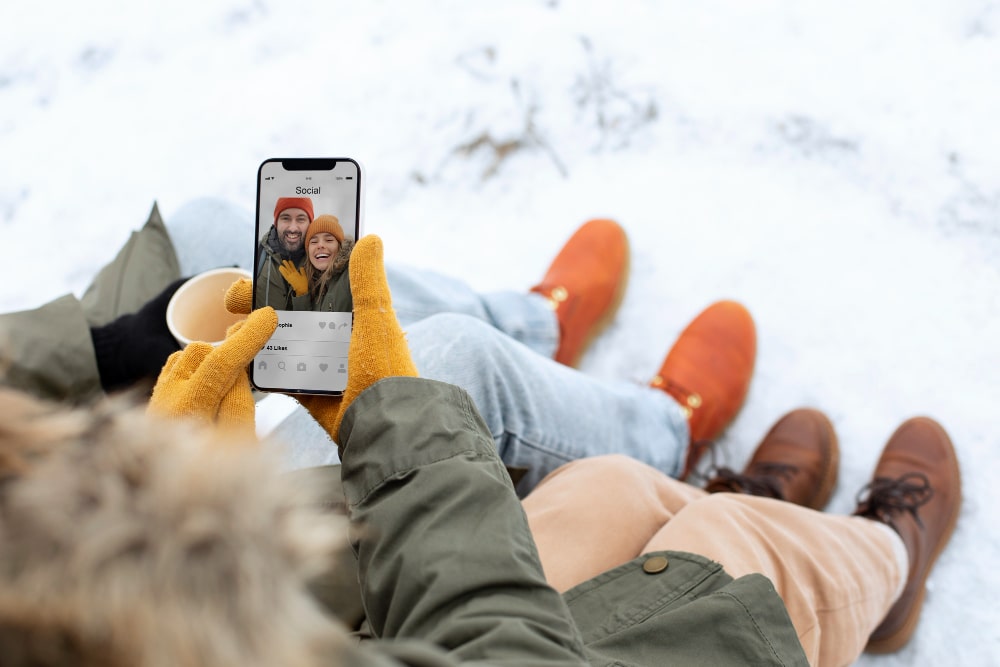 Paar hält Smartphone im Schnee – gemeinsame Social-Media-Momente mit eSIM Schweiz teilen