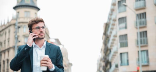 swiss businessman street holding takeaway coffee cup hand talking mobile phone 540x250