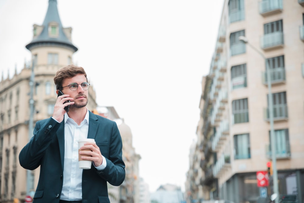 Schweizer Geschäftsmann mit Coffee-to-go telefoniert unterwegs – jederzeit erreichbar mit eSIM Schweiz